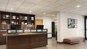 A reception area with a wooden counter, shelves with various items, a bench, and framed pictures on the wall. - Four Points by Sheraton Raleigh Arena (Raleigh)