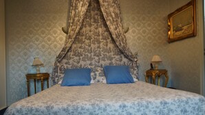 A bedroom with a canopy bed, two bedside tables with lamps, patterned wallpaper, and a framed picture on the wall. - Hotel La Diligence (Honfleur)