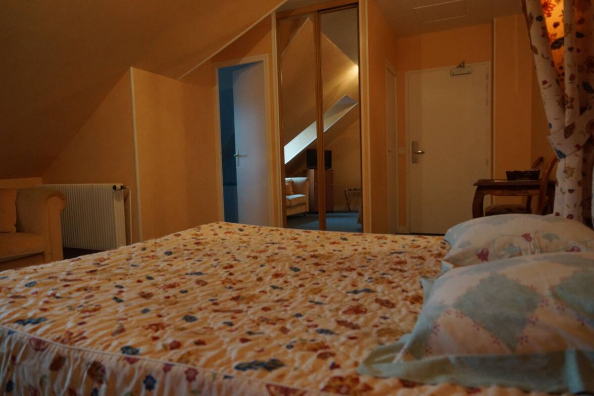 A bedroom with a bed, a chair, a radiator, and a door leading to a staircase.