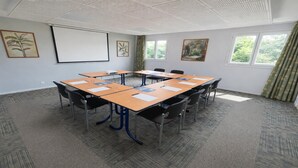 A conference room with a large table, chairs, a projector screen, and artwork on the walls. - Kyriad Montpellier Centre - Antigone (Montpellier)