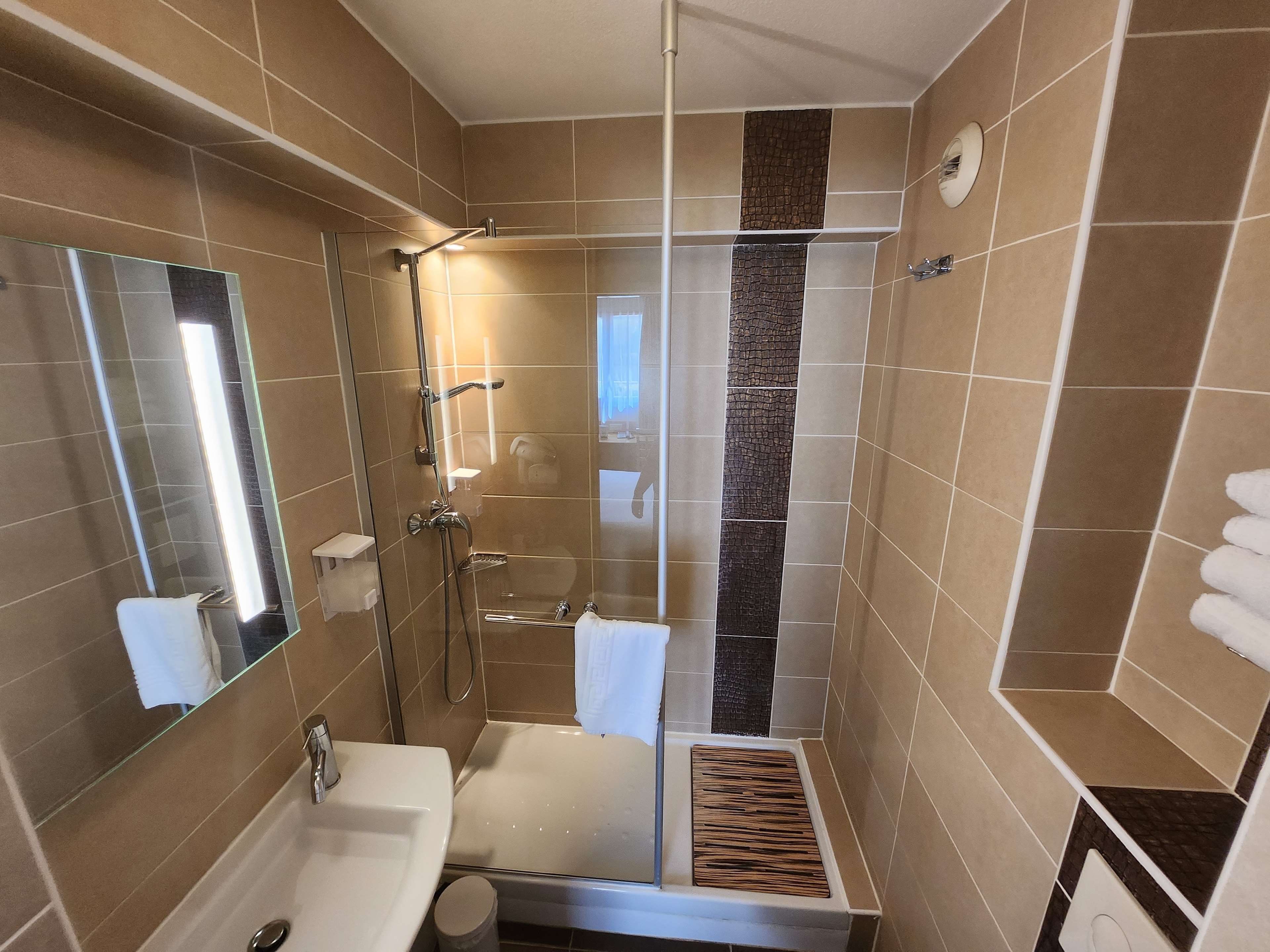 Une salle de bain moderne avec une douche à parois de verre, un lavabo blanc et un miroir.