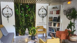 A cozy interior with a green wall, a Buddha statue, a bookshelf, and comfortable seating. - Kyriad Montpellier Centre - Antigone (Montpellier)