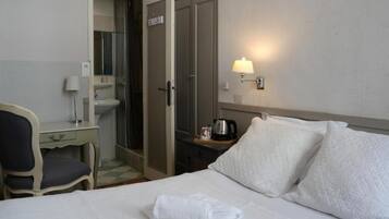 Une chambre d’hôtel comprenant un lit, un bureau avec une chaise, un lavabo, un miroir et une table de chevet avec une lampe.