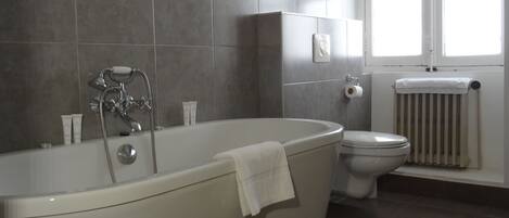 Un baño moderno con una bañera independiente, un inodoro y un ventanal.