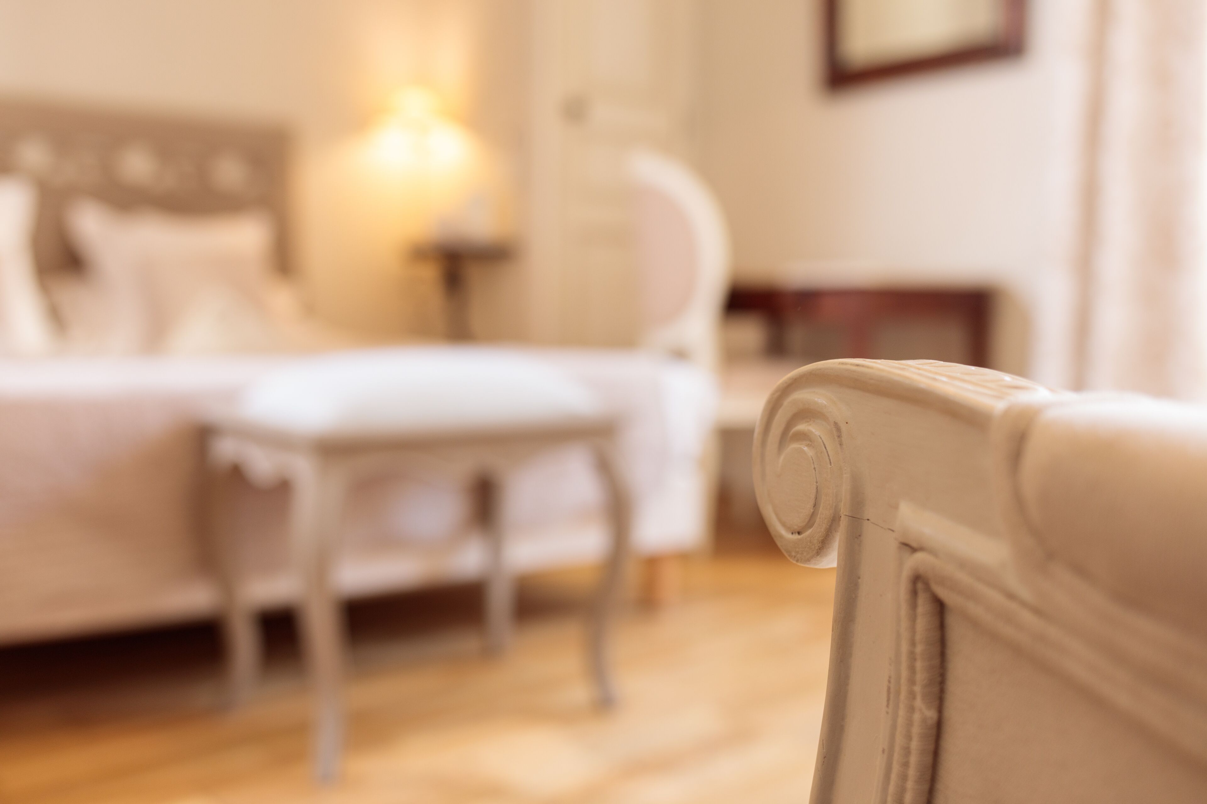 A hotel room with a bed, a bedside table, and a chair.