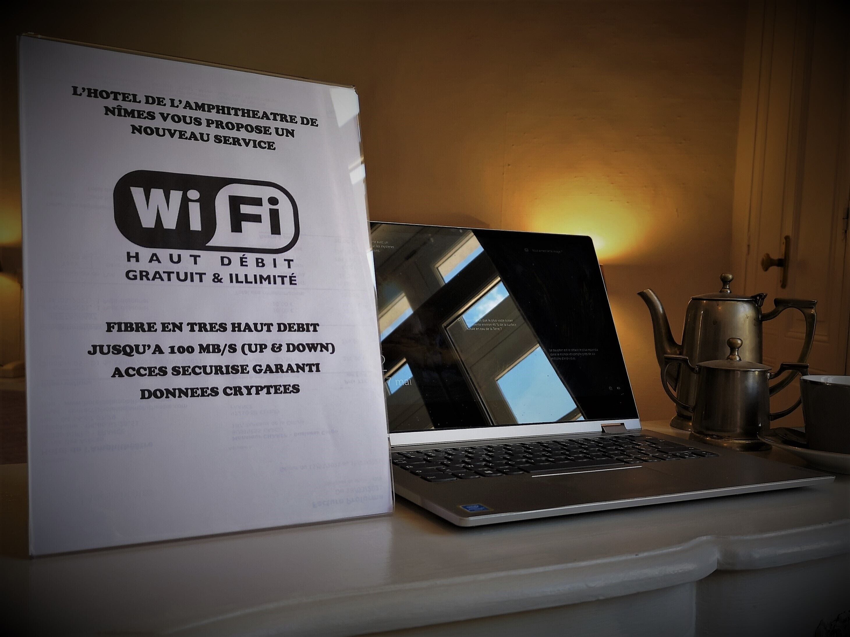 Ein Laptop auf einem Tisch, mit einem Schild zur Information über WLAN-Verfügbarkeit und Sicherheit.
