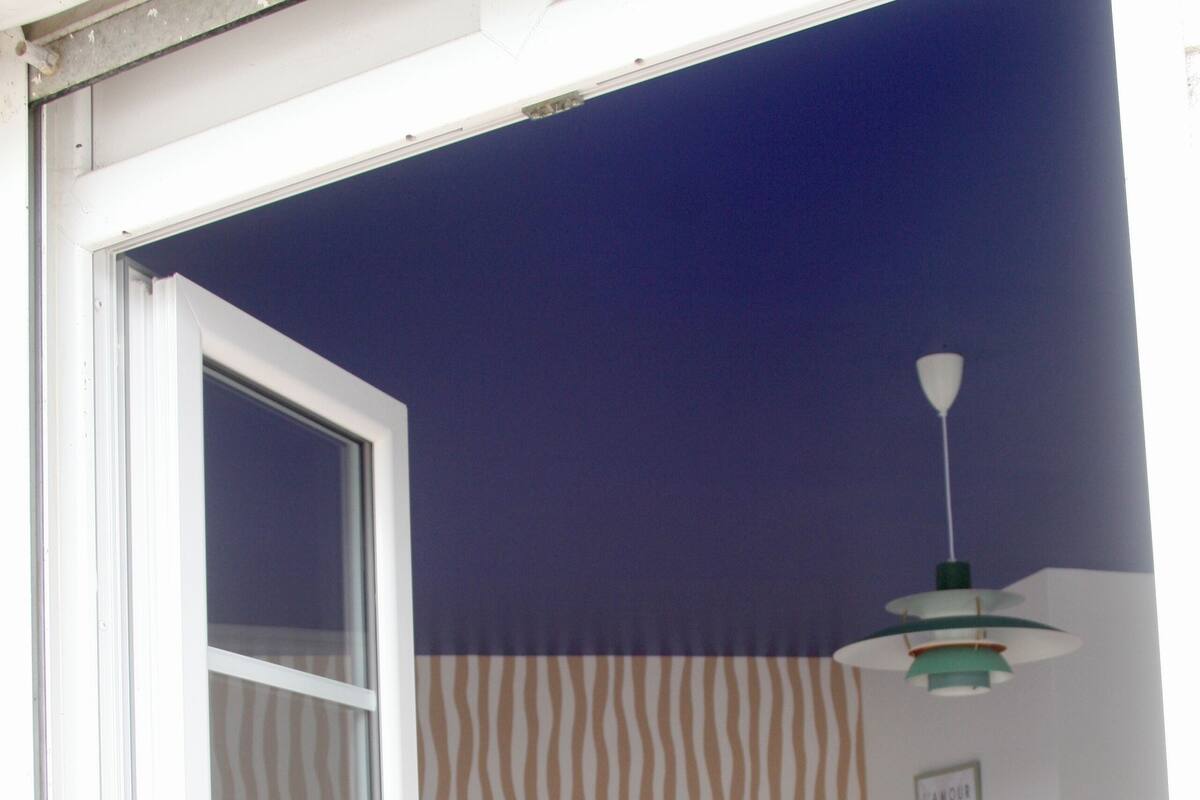 A room with a bed, a chair, and a patterned wall.