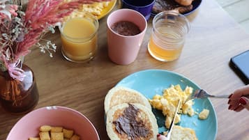 A breakfast table with plates of food, a vase of flowers, and a smartphone.