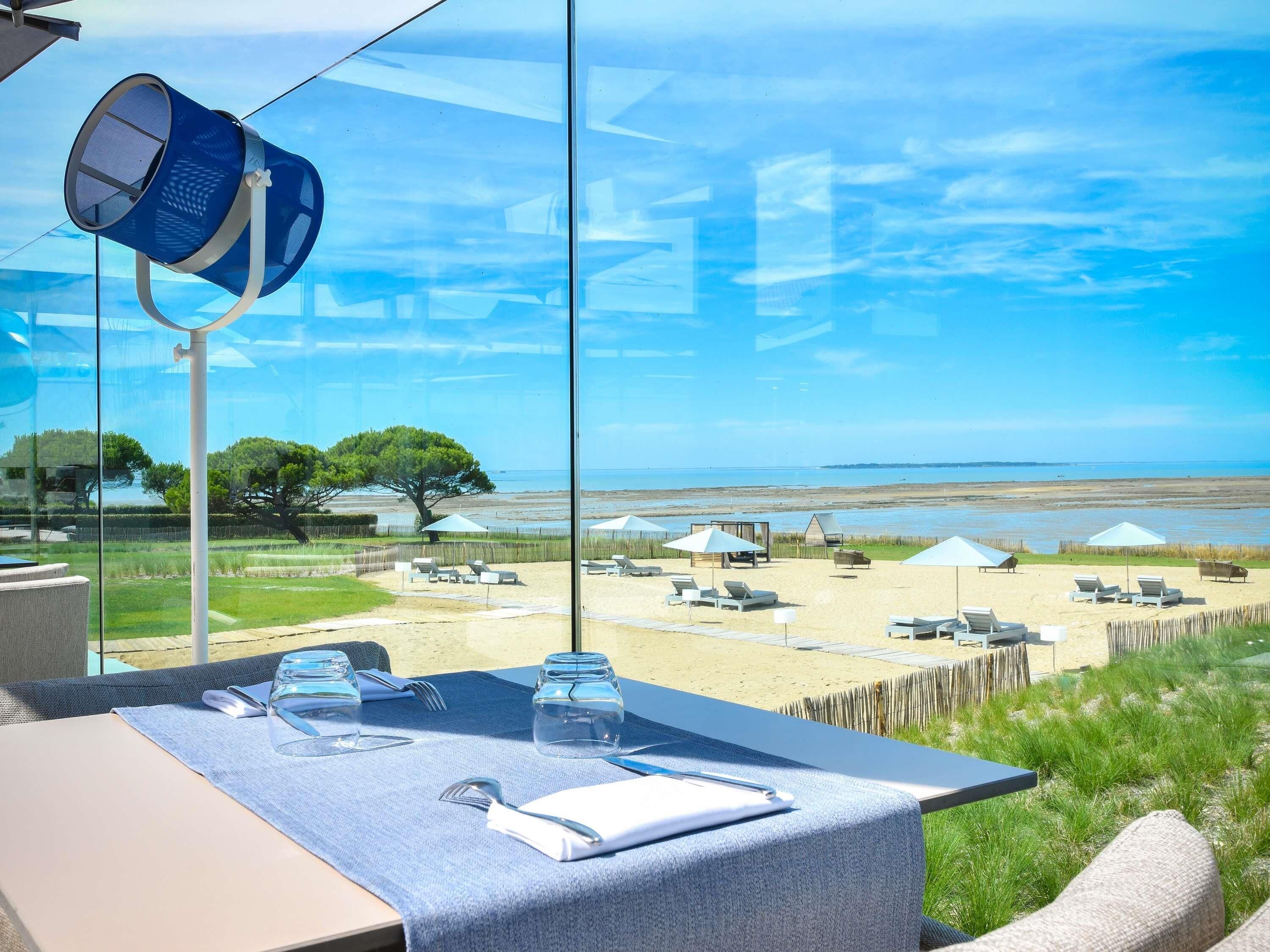 A dining table with a view of a beach and ocean.