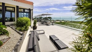 A modern outdoor patio with seating, a pool, and a view of the sea. - La Grande Terrasse Hotel & Spa La Rochelle - MGallery Collection (Chatelaillon-Plage)