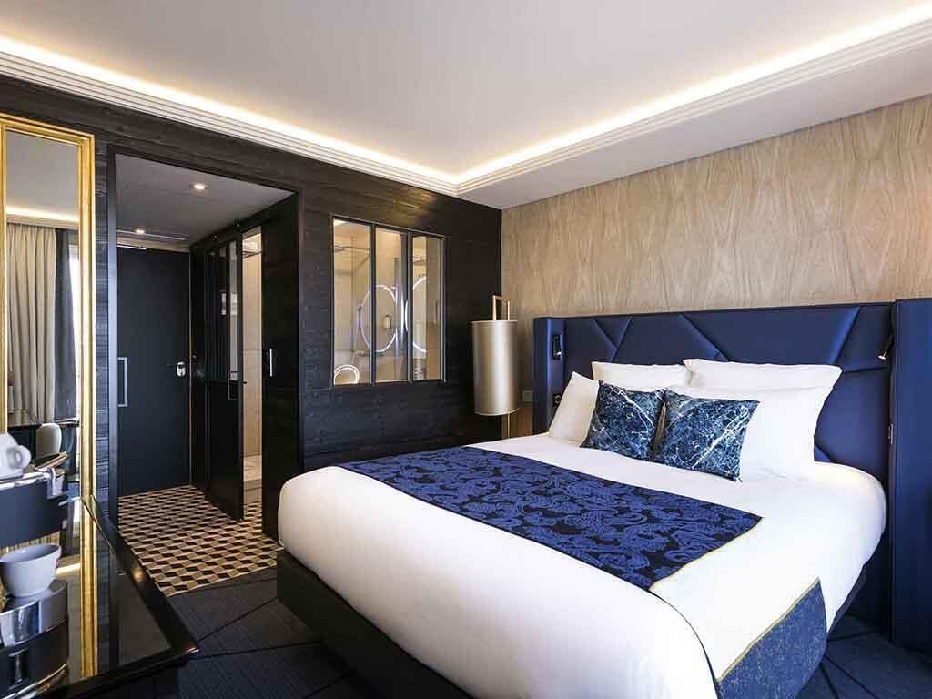Una habitación de hotel moderna con una cama grande, baño independiente y vestidor.