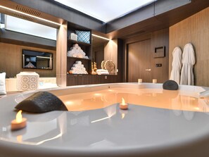 A modern spa room with a hot tub, towels, and a shelf with toiletries. - La Grande Terrasse Hotel & Spa La Rochelle - MGallery Collection (Chatelaillon-Plage)