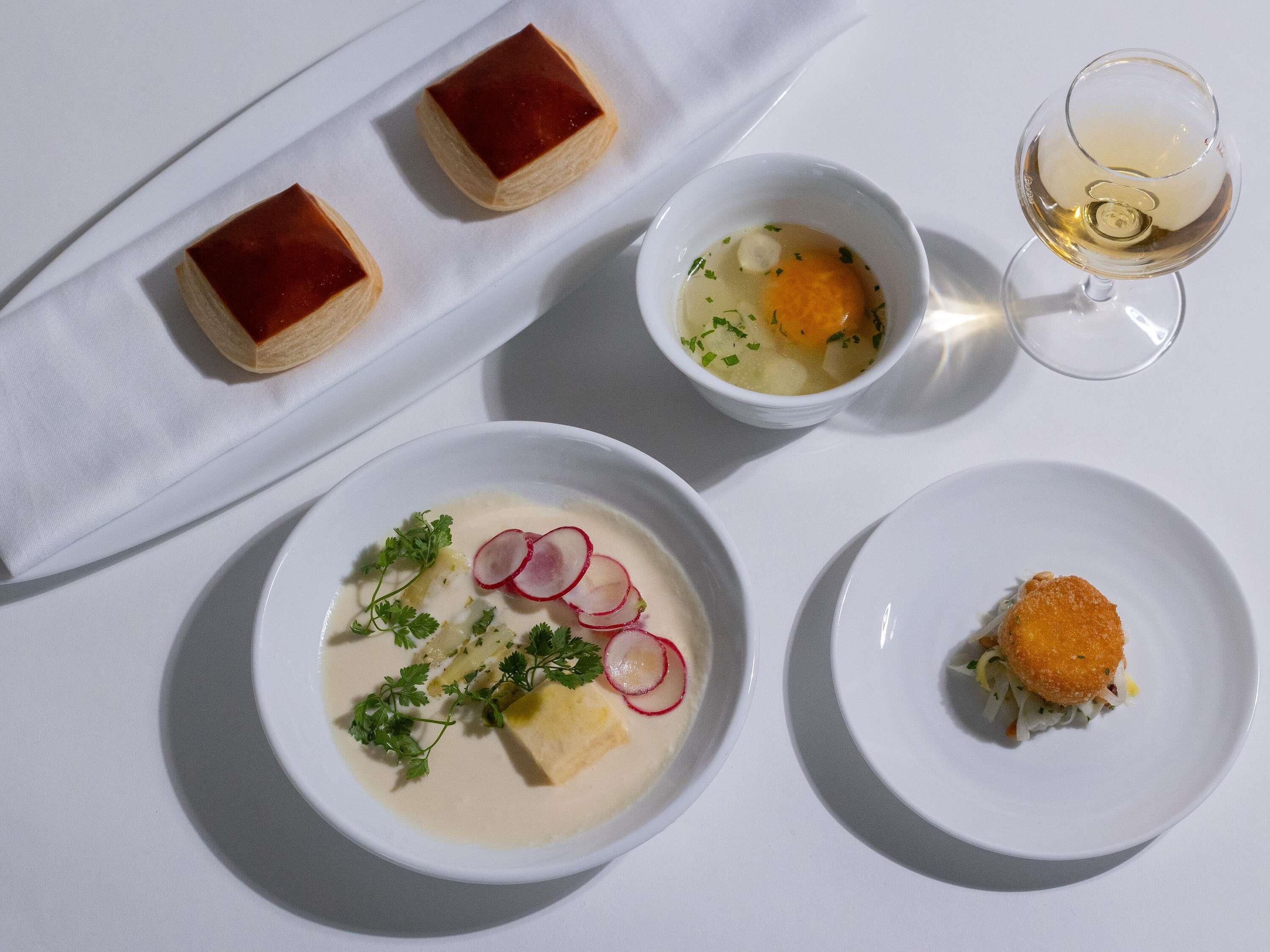 Una mesa con un postre, sopa y una copa de vino.