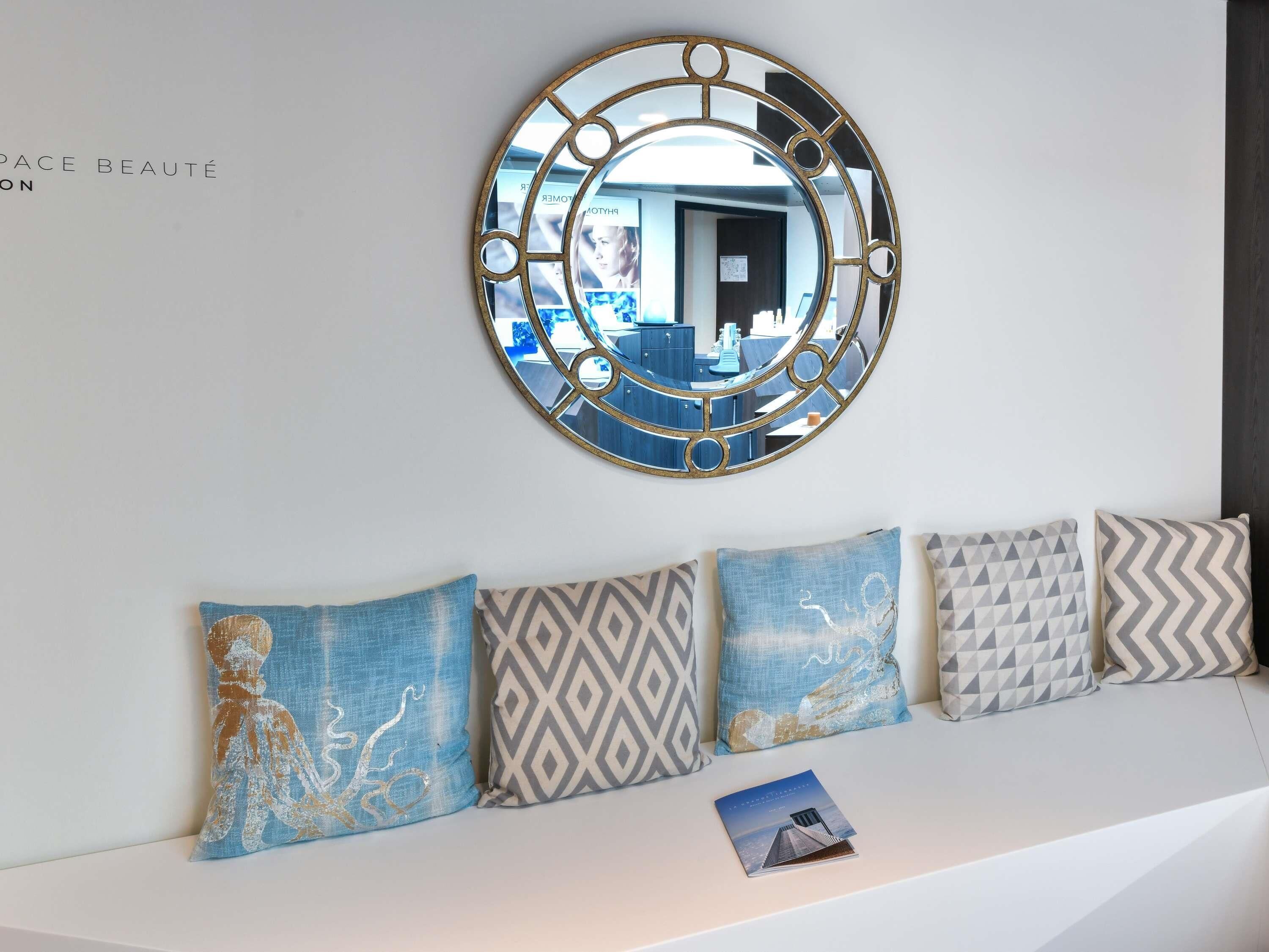 A wall with a decorative mirror and a row of patterned cushions.
