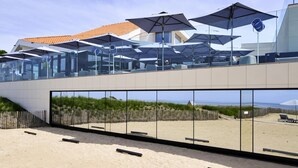 A modern beachside restaurant with outdoor seating and a view of the beach. - La Grande Terrasse Hotel & Spa La Rochelle - MGallery Collection (Chatelaillon-Plage)