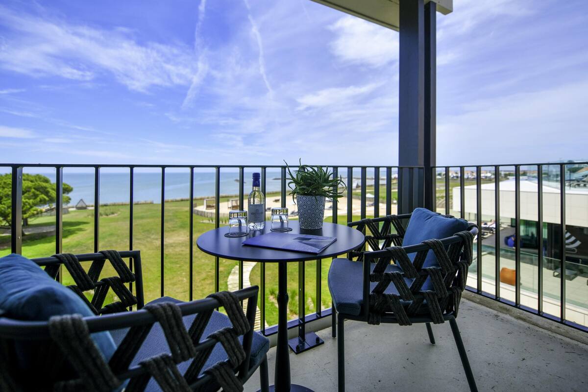 A balcony with a table, chairs, and a potted plant.