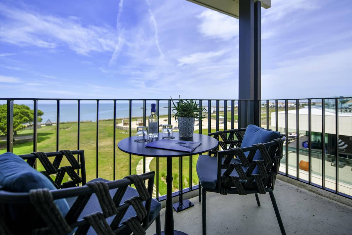 A balcony with a table, chairs, and a potted plant.