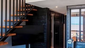 A modern interior with a staircase, a flat-screen TV, a patterned floor, and a black cabinet.