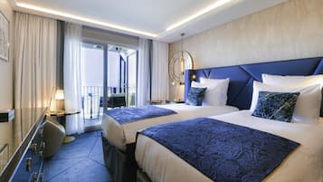 Ein Hotelzimmer mit zwei Betten, einem Schreibtisch, einem Stuhl, einer Lampe und Blick nach draußen.
