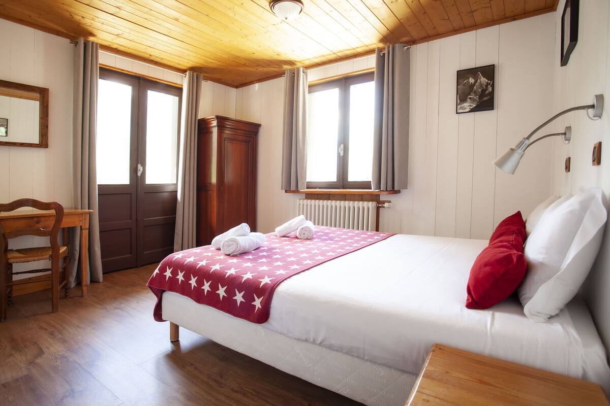 Un dormitorio ordenado con una cama, un escritorio de madera y una silla.