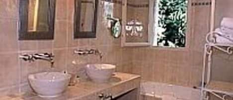 Un baño con dos lavamanos, una ventana y un perchero para toallas.