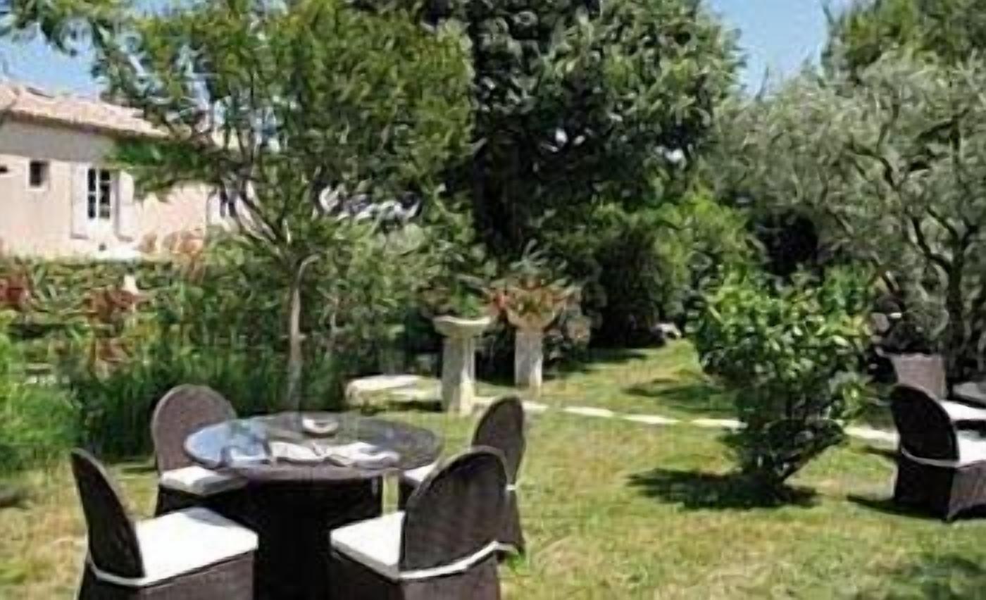An outdoor seating area with round tables and chairs, surrounded by greenery and trees.