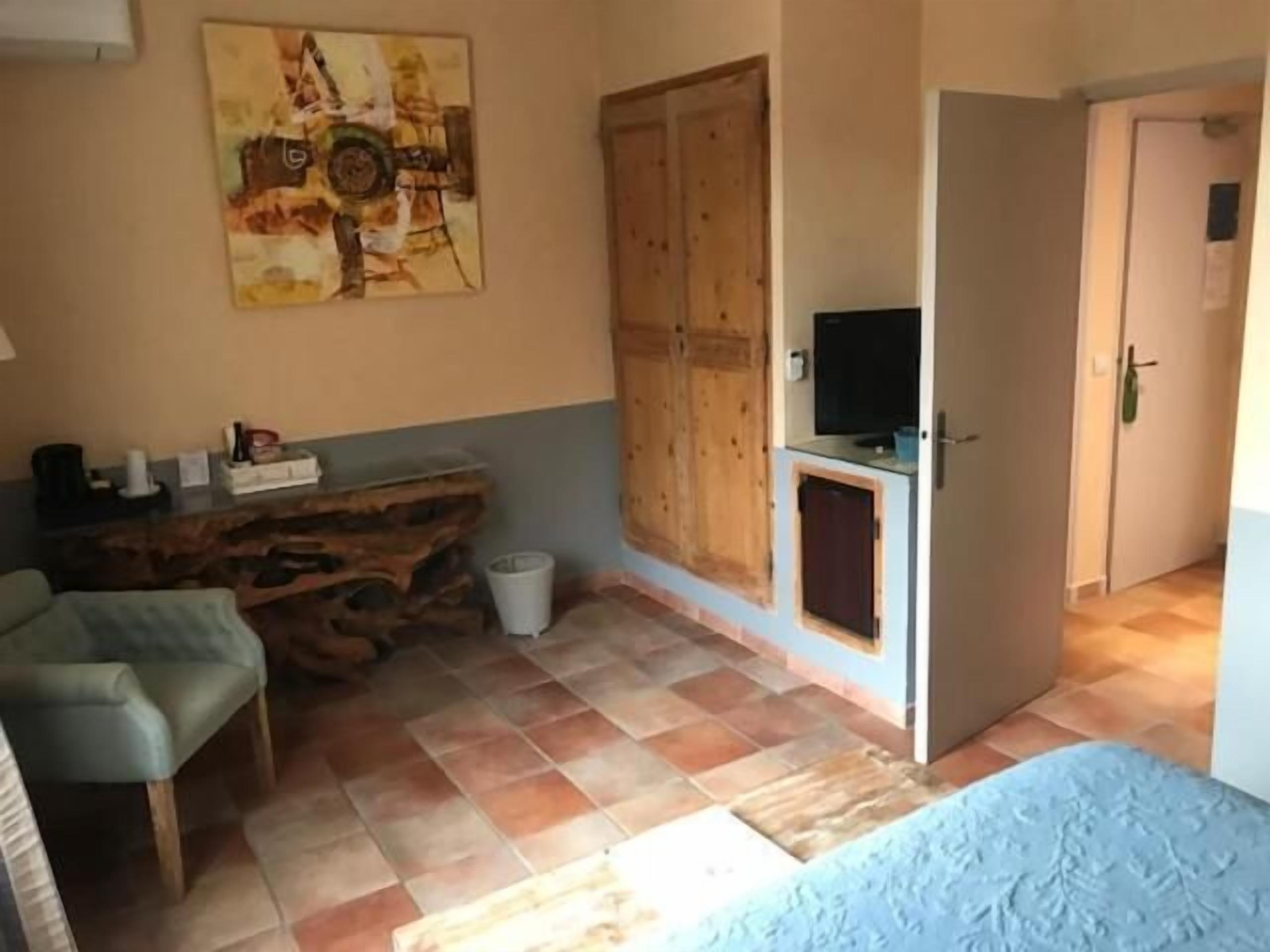 A room with a wooden desk, a chair, a television, and a bed.