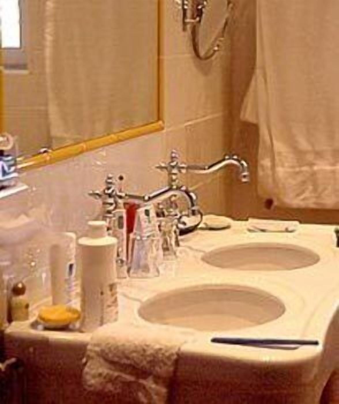 A bathroom with a double sink, a mirror, and a towel rack.