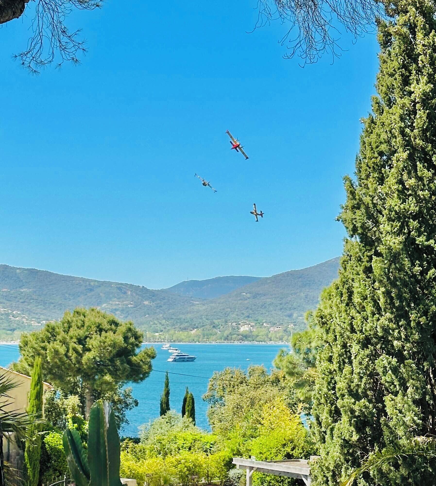 Eine Küstenlandschaft mit klarem Himmel, einem Gewässer und ein paar Flugzeugen im Flug.