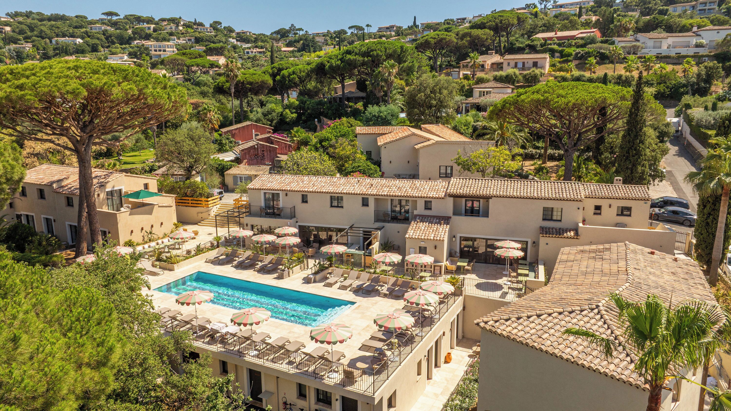 A hotel with a swimming pool, outdoor seating, and a view of the surrounding hillside.