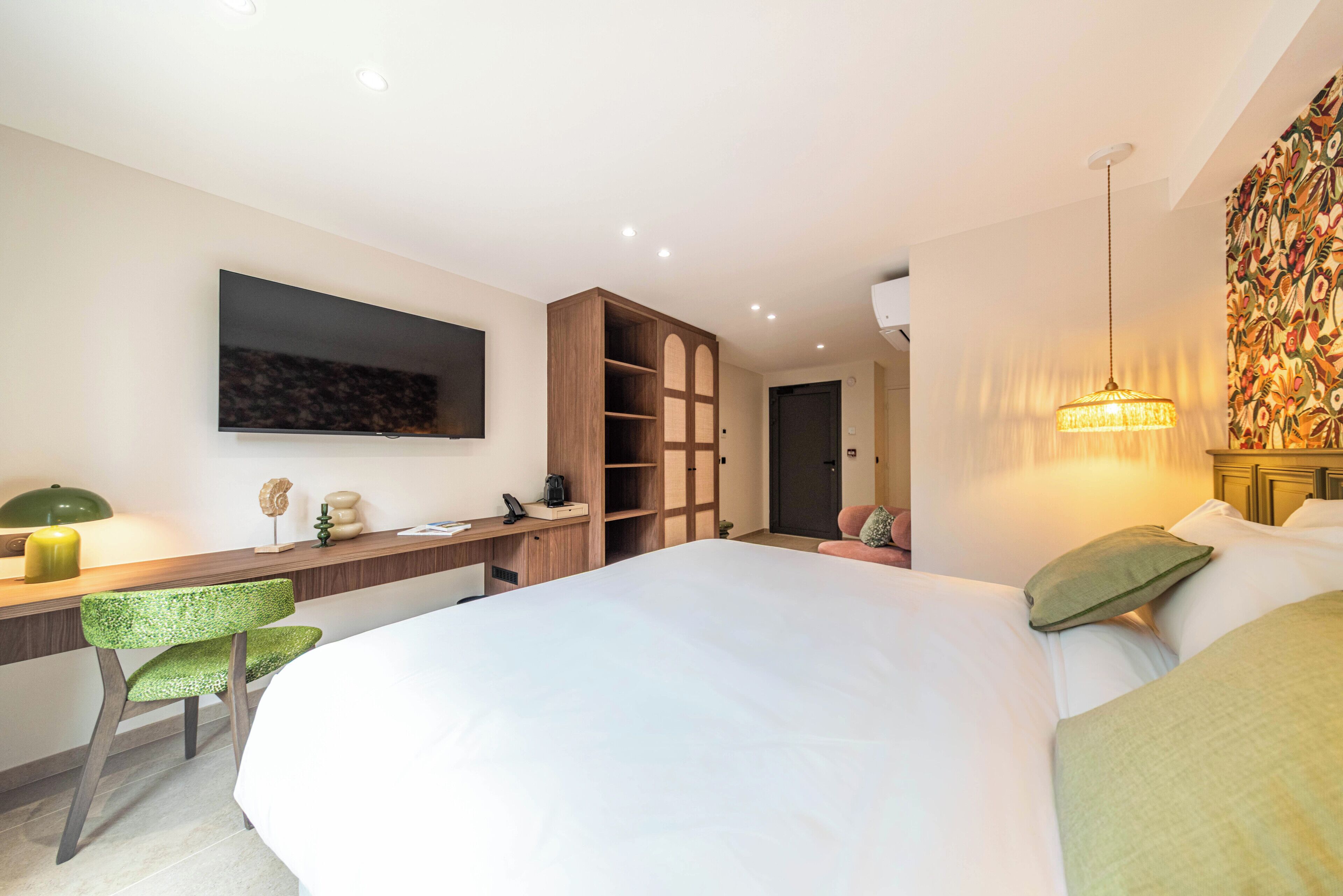 Una habitación de hotel con cama, escritorio, silla, armario y televisor.