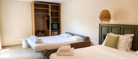 A hotel room with two beds, a television, a wardrobe, and a bench.