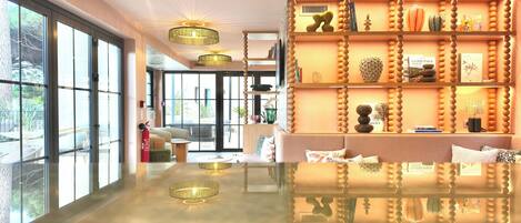 A modern hotel lobby with large windows, a reflective floor, and decorative chandeliers.