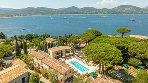 Una villa costera con piscina, zona de estar y vistas al mar y las montañas.