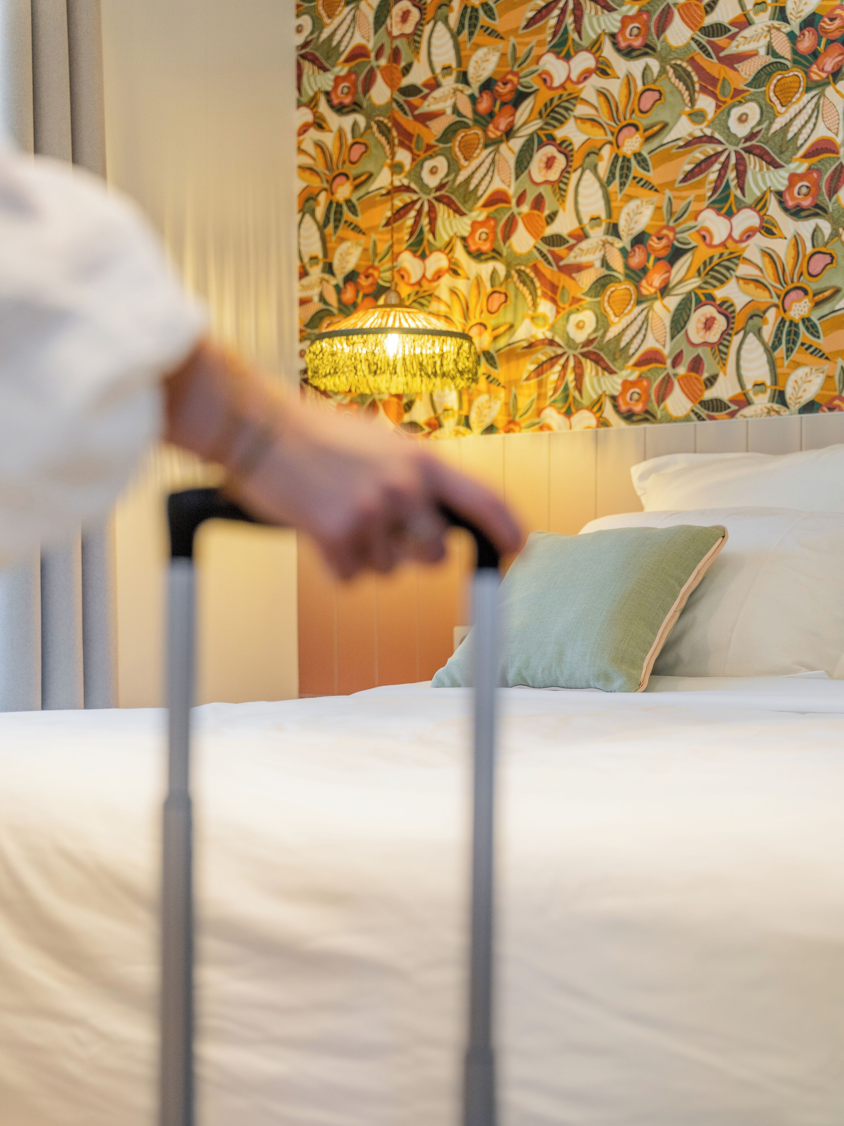 Una camera d'albergo con un letto, una parete decorativa e un lampadario.