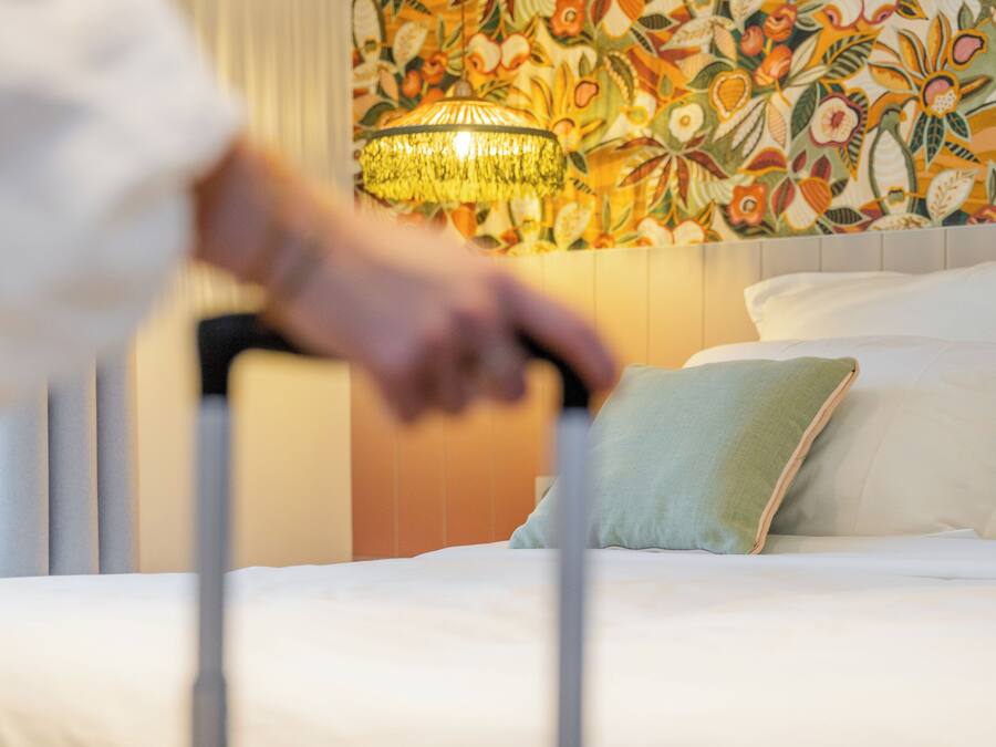 Una camera d'albergo con un letto, una parete decorativa e un lampadario.