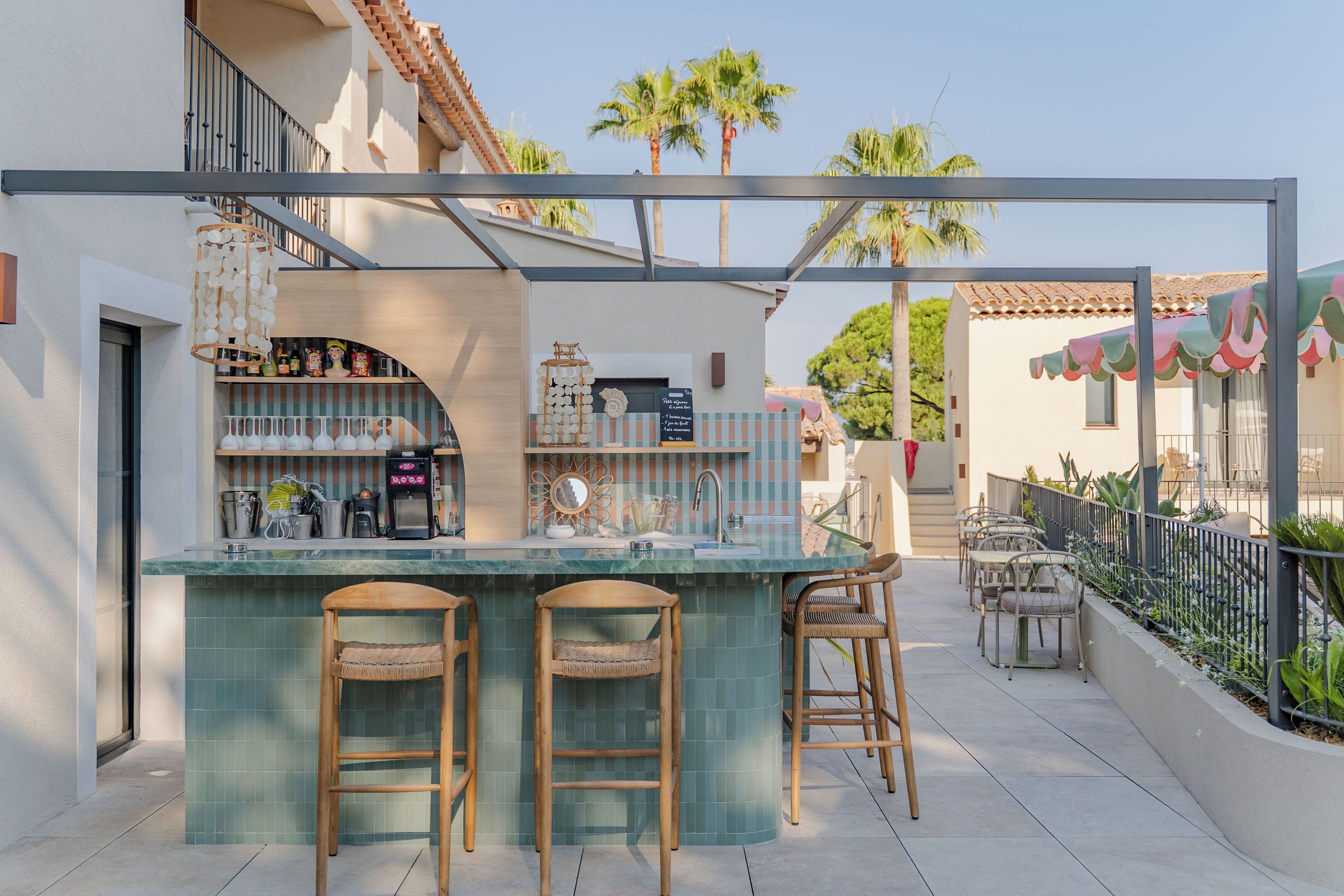 Un espace bar doté d’un comptoir carrelé, de tabourets et d’une variété de bouteilles et de verres.