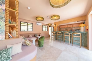 A modern interior with a bar area, seating, and a kitchen. - Hôtel Les Capucines - Saint Tropez (Gassin)