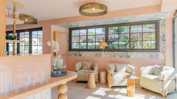 Una habitación luminosa con un ventanal grande, dos sillones, una mesita y una zona de bar con una lámpara decorativa.