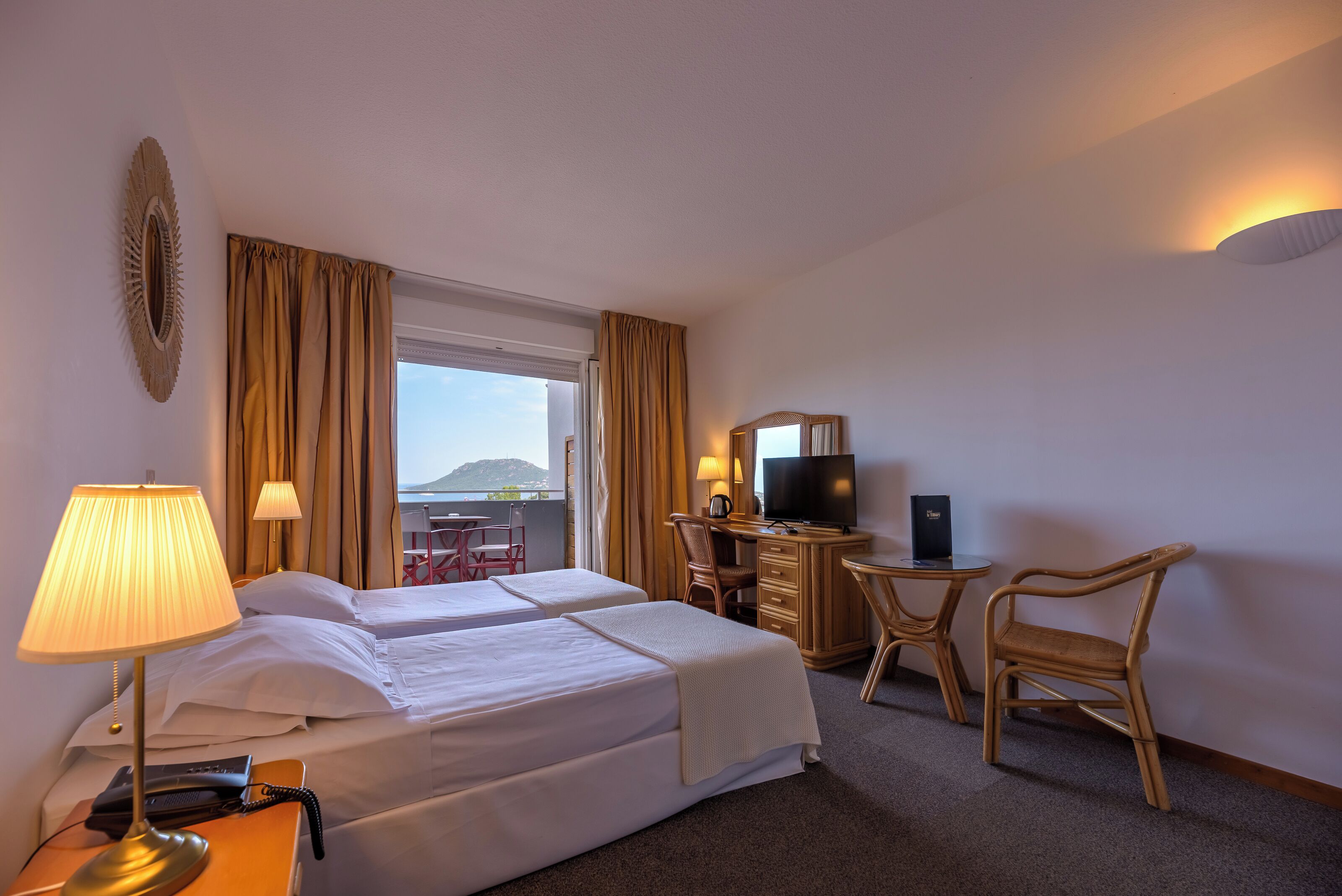 Une chambre d’hôtel avec deux lits, un bureau équipé d’une télévision, une chaise et une lampe.