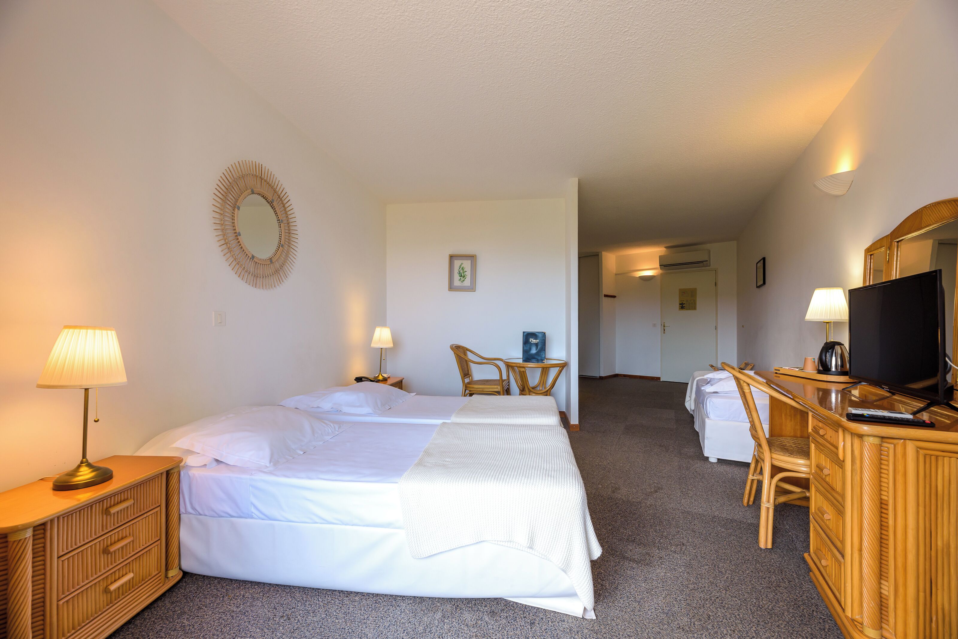 Une chambre d’hôtel comprenant un lit, des tables de chevet, un bureau, une chaise, une télévision et une petite table avec une lampe.