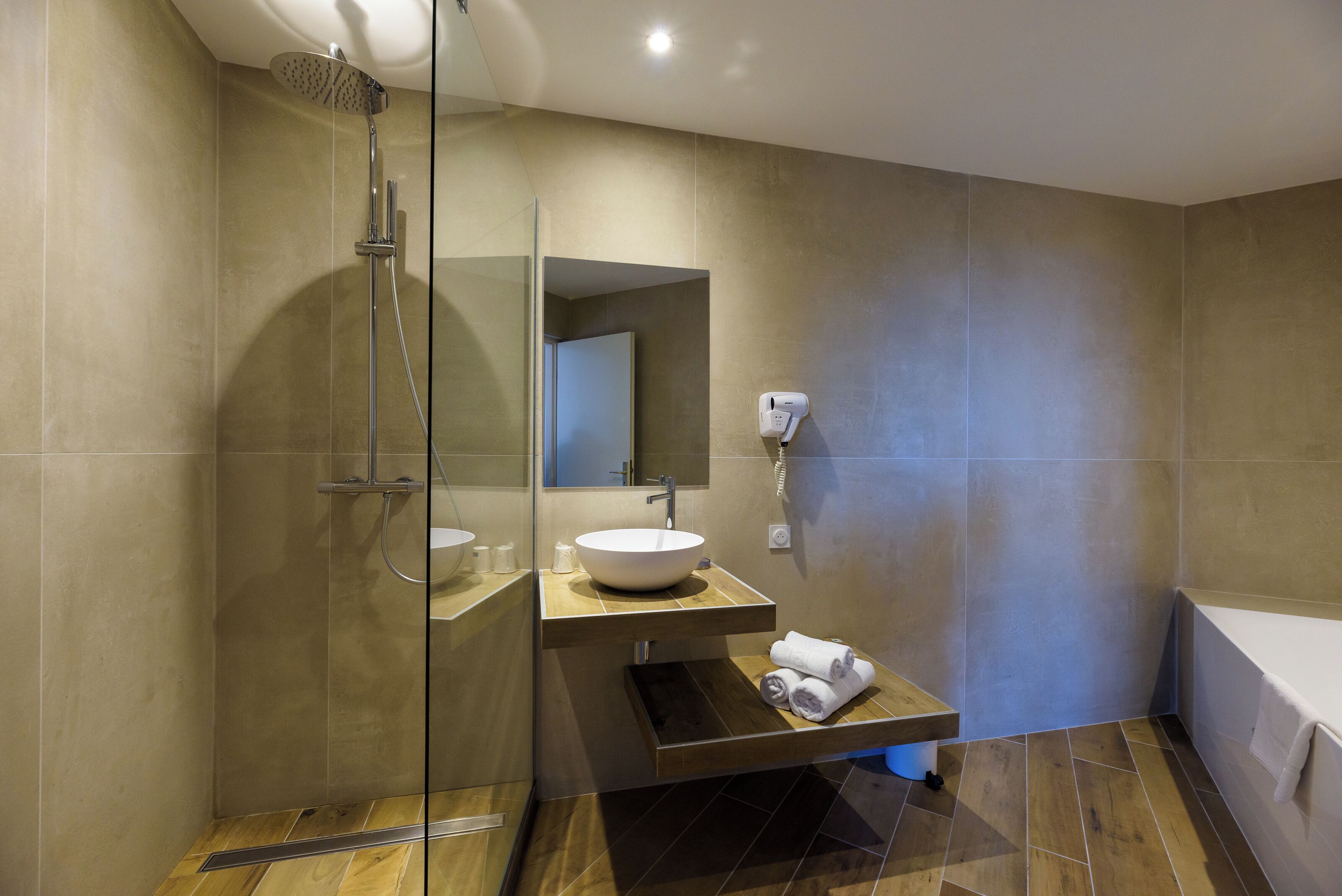 A modern bathroom with a glass shower enclosure, a sink, a mirror, and a towel rack.