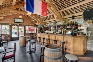 A bar area with wooden stools, a bar counter, and a stone wall.