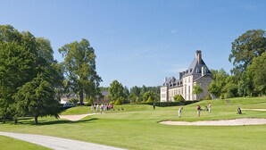 A golf course with a large building in the background. - Domaine Des Ormes (Epiniac)