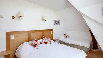 A hotel room with two beds, a wooden headboard, white bedding, and a small bedside table.