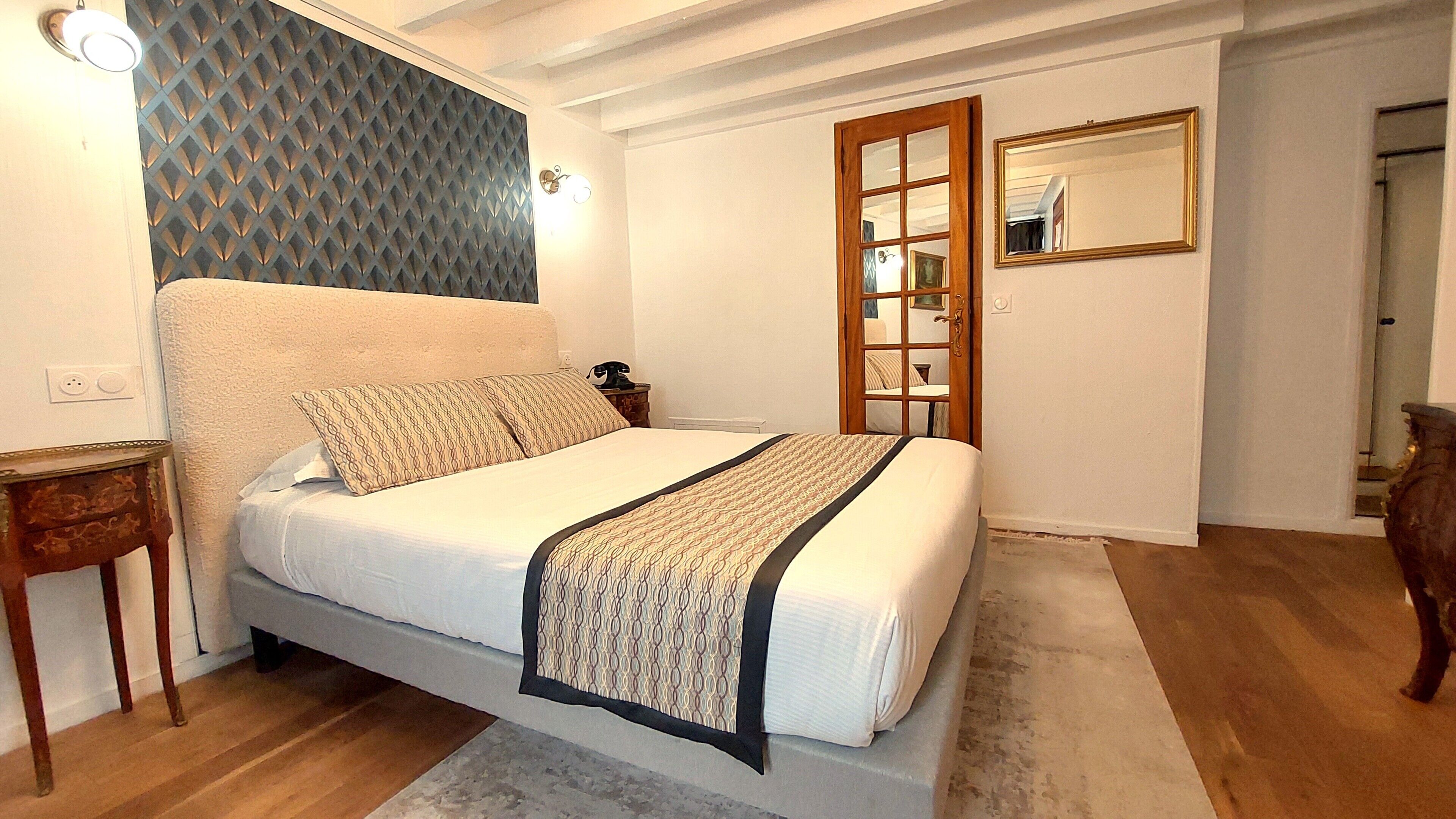 Quarto com cama, mesa de cabeceira e espelho na parede.