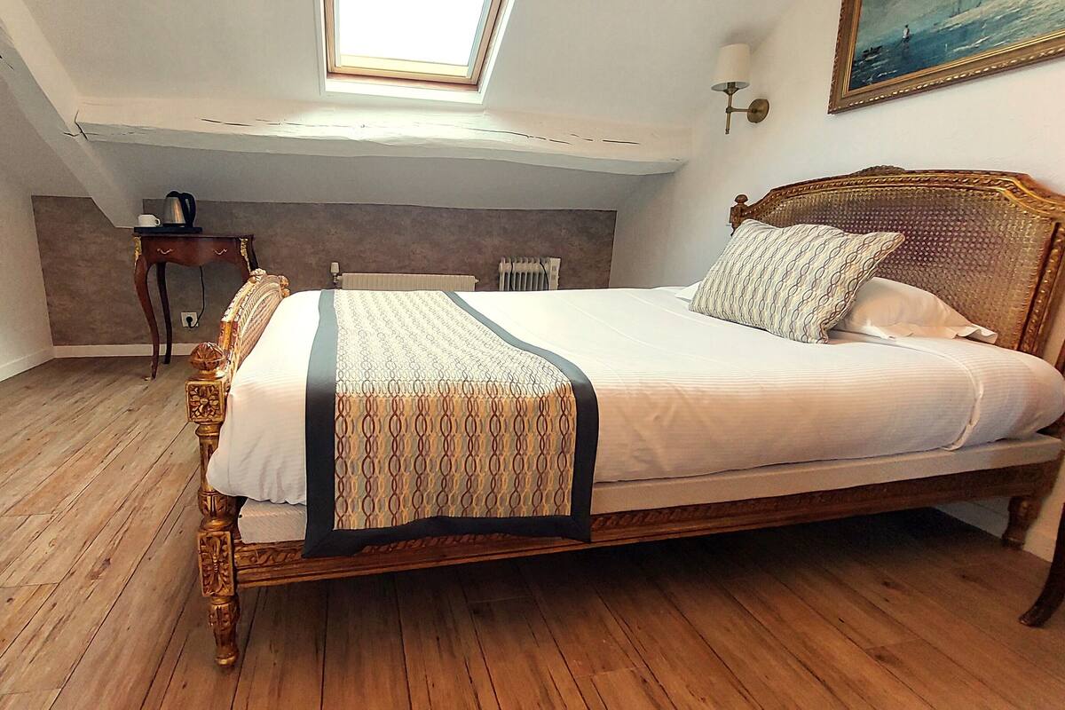 A bedroom with a wooden bed, a nightstand, a dresser, a radiator, and a skylight.