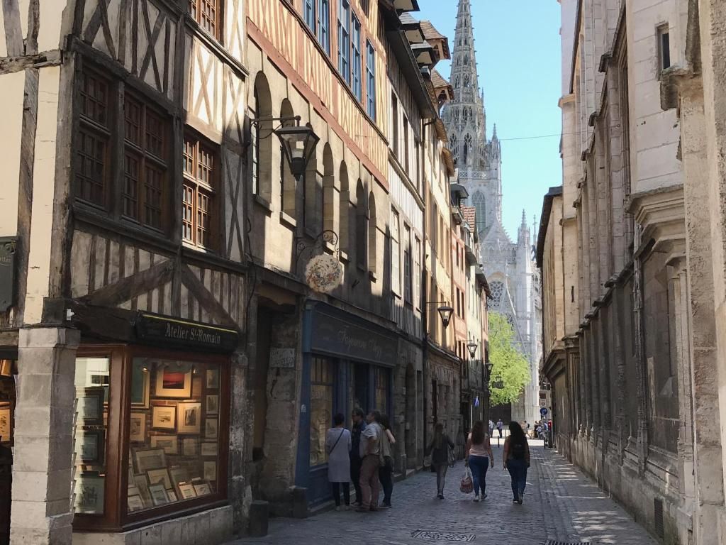 A narrow street lined with historic buildings, including a shop with a sign that reads 'Meller S-Romain.'