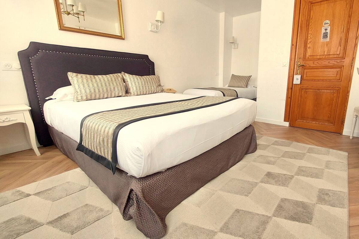 A bedroom with a bed, bedside tables, a desk, and a door.