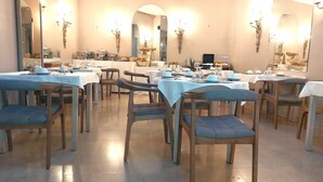 Uma área de refeições com várias mesas e cadeiras, completa com louças preparadas e luminárias.